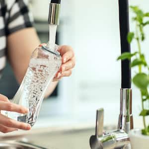 woman filling up water bottle in sink